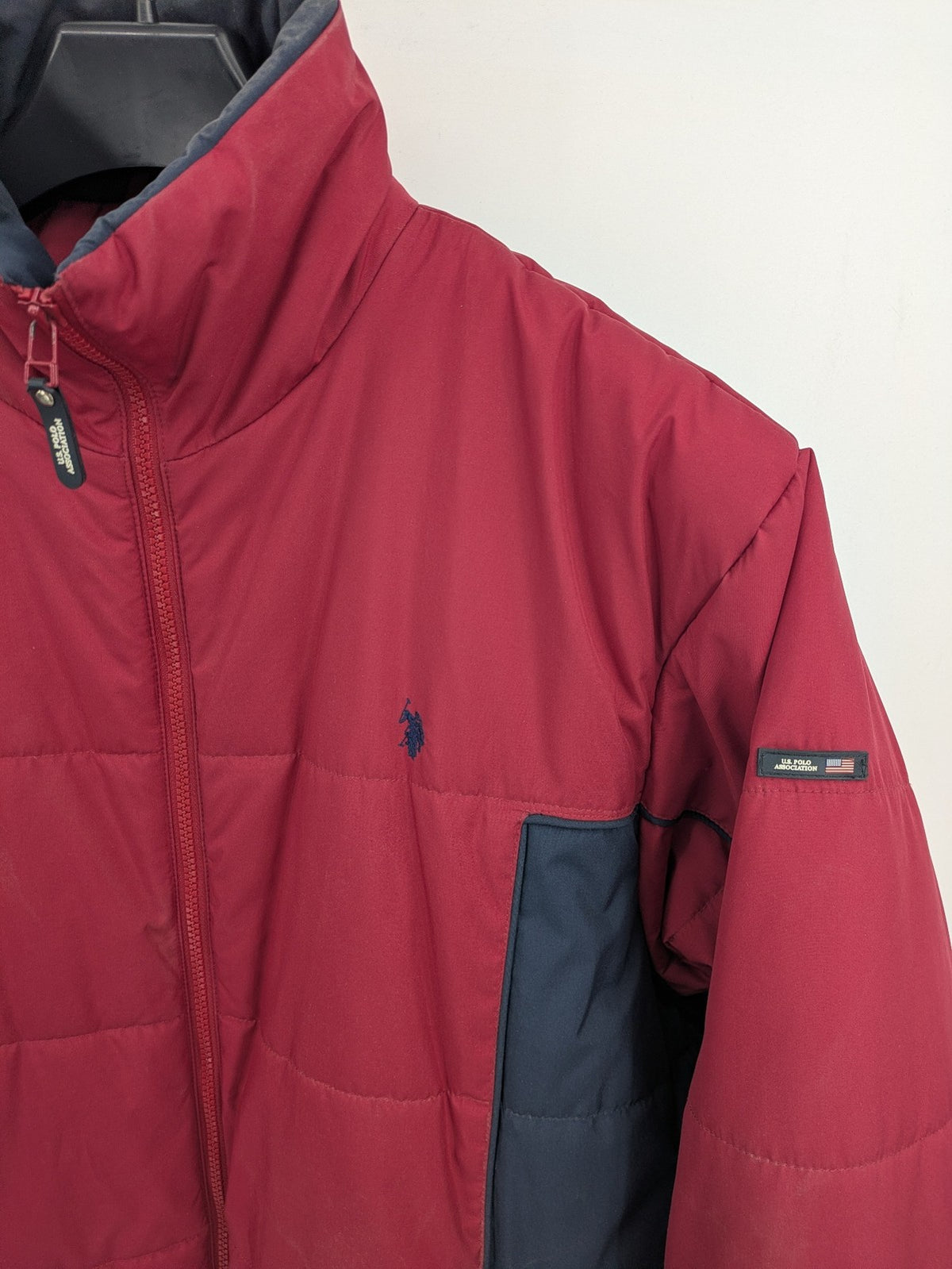 US Polo Assn. puffer jacket navy red two-tone design with embroidered logo and zip pockets.