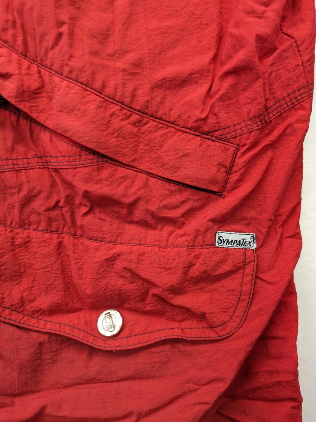 Bush Sportswear red trekking jacket with front zipper, multiple pockets, and striped lining.