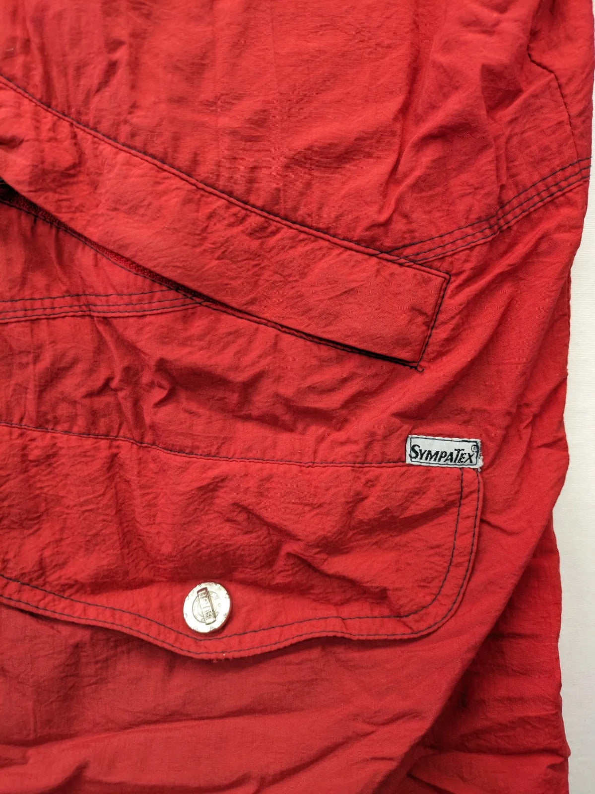 Bush Sportswear red trekking jacket with front zipper, multiple pockets, and striped lining.
