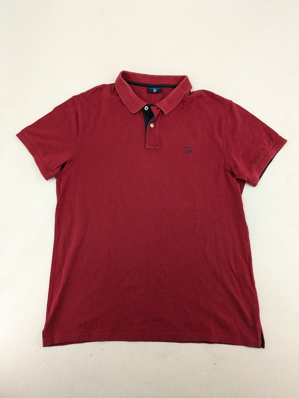 GANT burgundy polo shirt with embroidered shield logo and contrasting navy collar details.