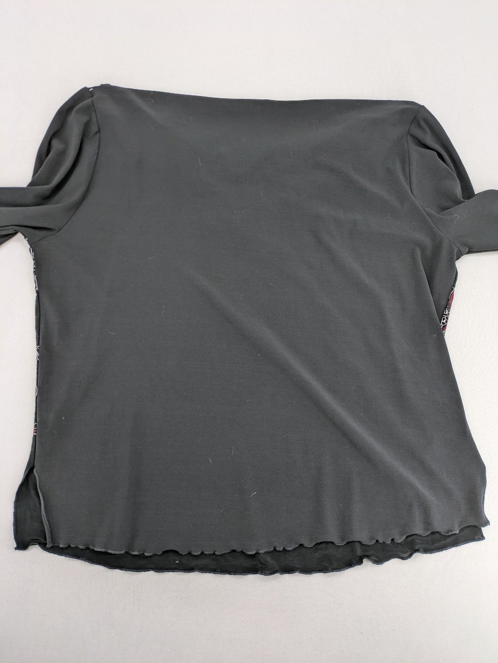 Damen black top with burgundy and white floral print, waterfall collar, and ruffled sleeves.