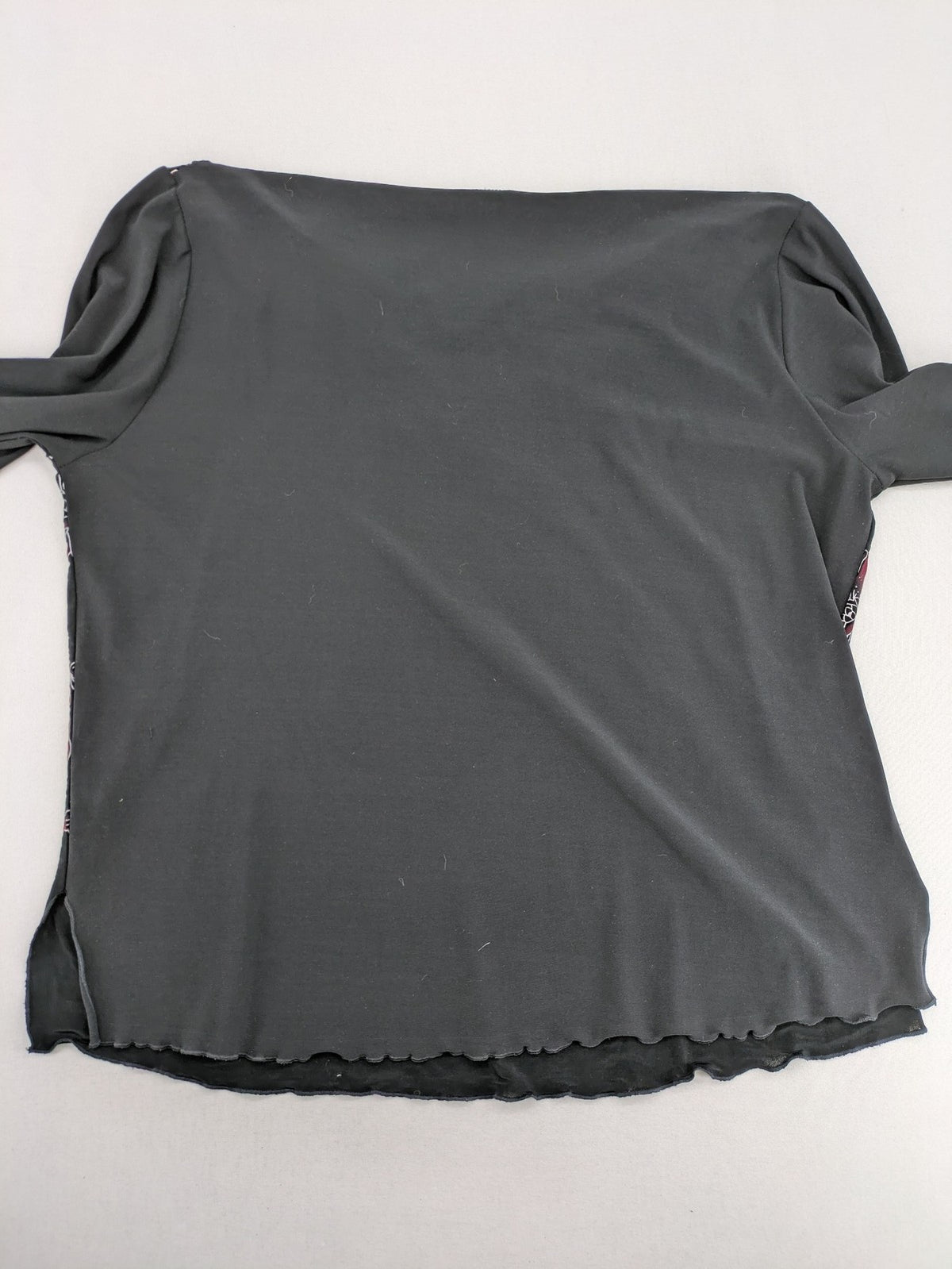 Damen black top with burgundy and white floral print, waterfall collar, and ruffled sleeves.