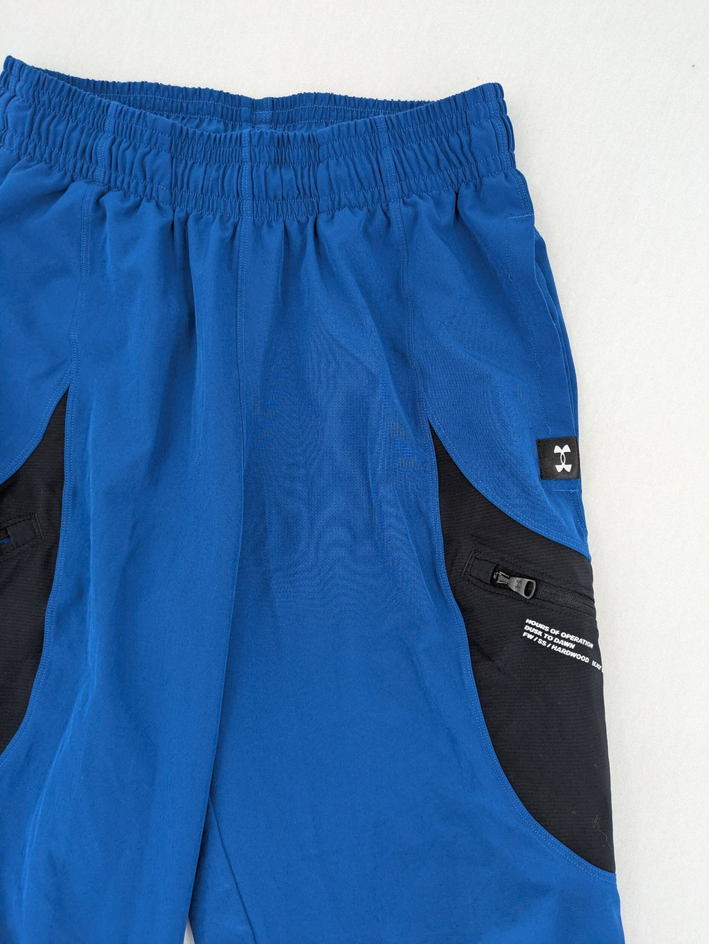Under Armour blue HeatGear joggers with black accents and zippered cargo pockets.