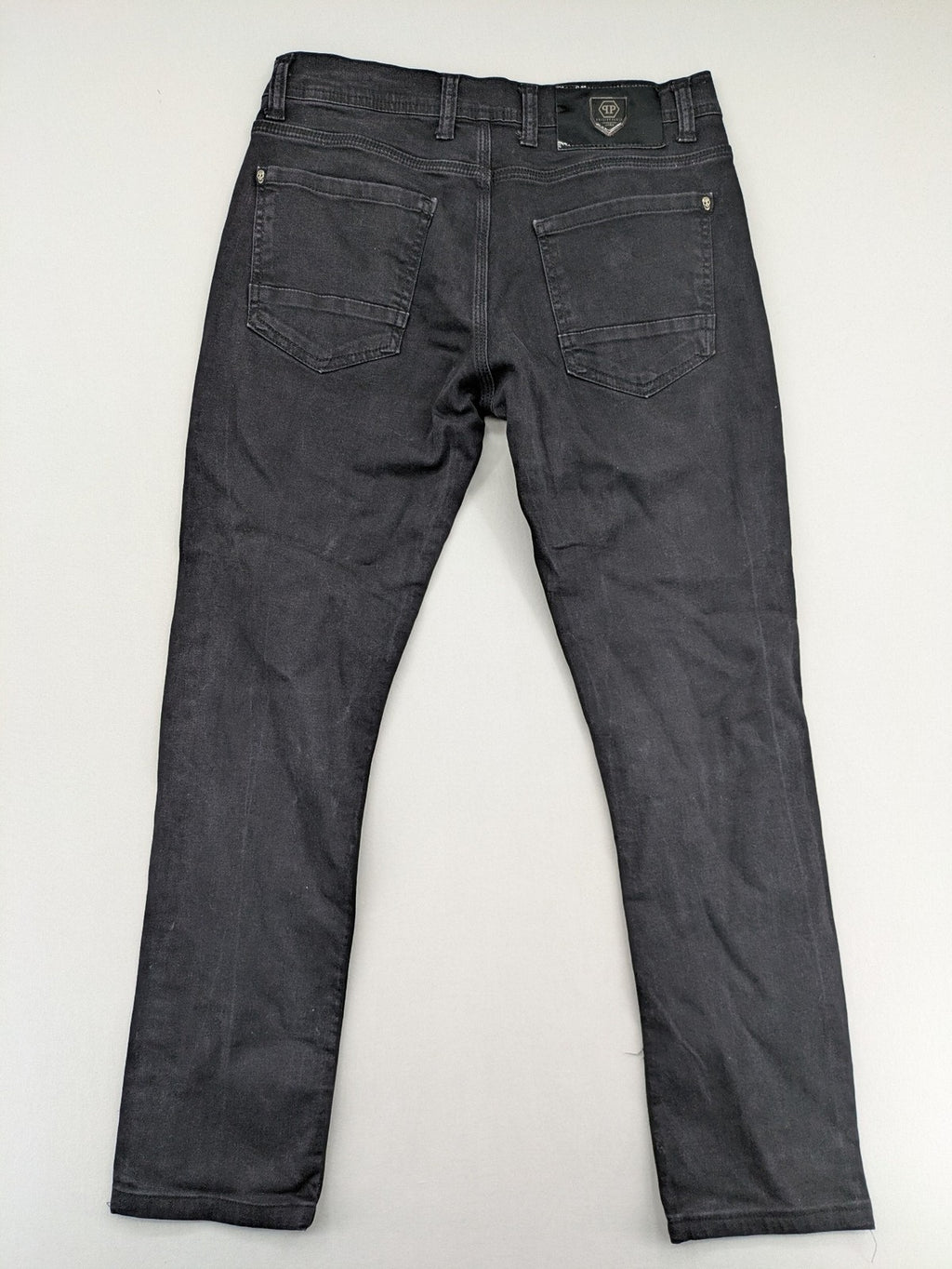 Philipp Plein black straight jeans with distressed finish and skull patch detail.