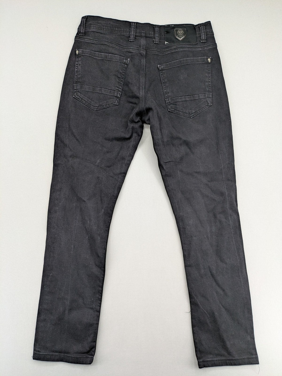 Philipp Plein black straight jeans with distressed finish and skull patch detail.