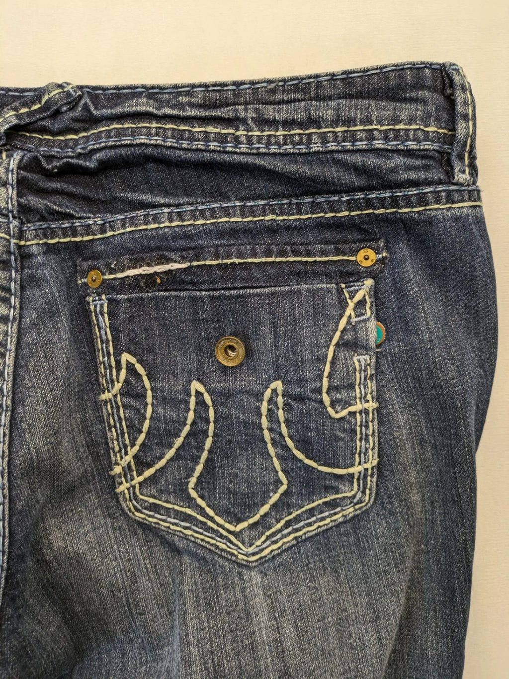 Rhodes blue skinny jeans with decorative studs and intricate embroidery on back pockets.