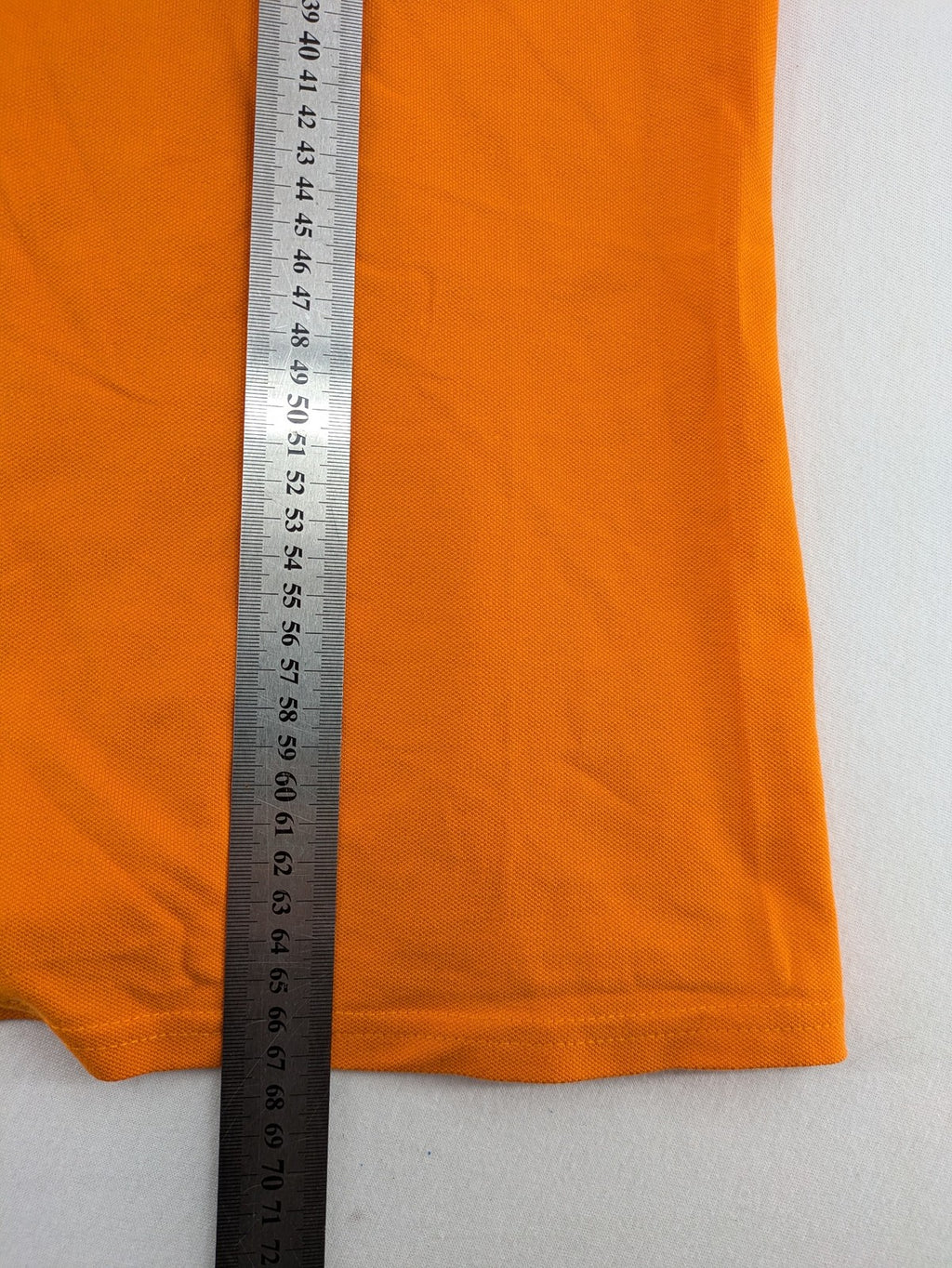 Teejays orange polo shirt with embroidered logo, classic collar, and button placket.