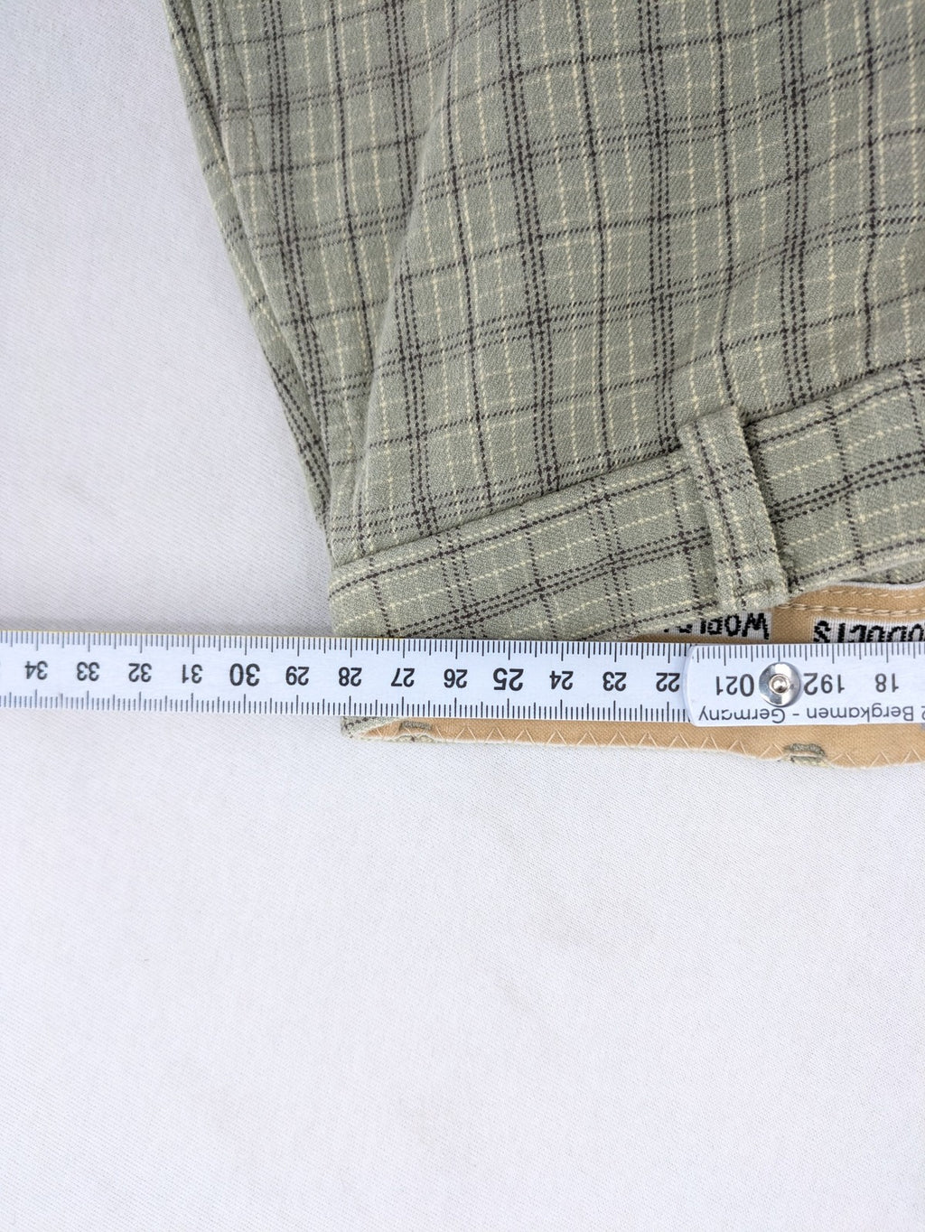 Jodhpur beige and grey riding pants with green check pattern and knee patches.