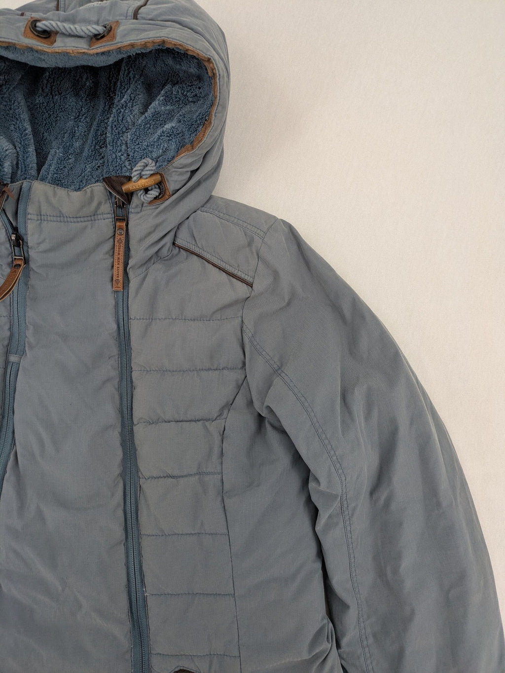 Naketano blue jacket with teddy fleece lining, hood, and leather appliqués.