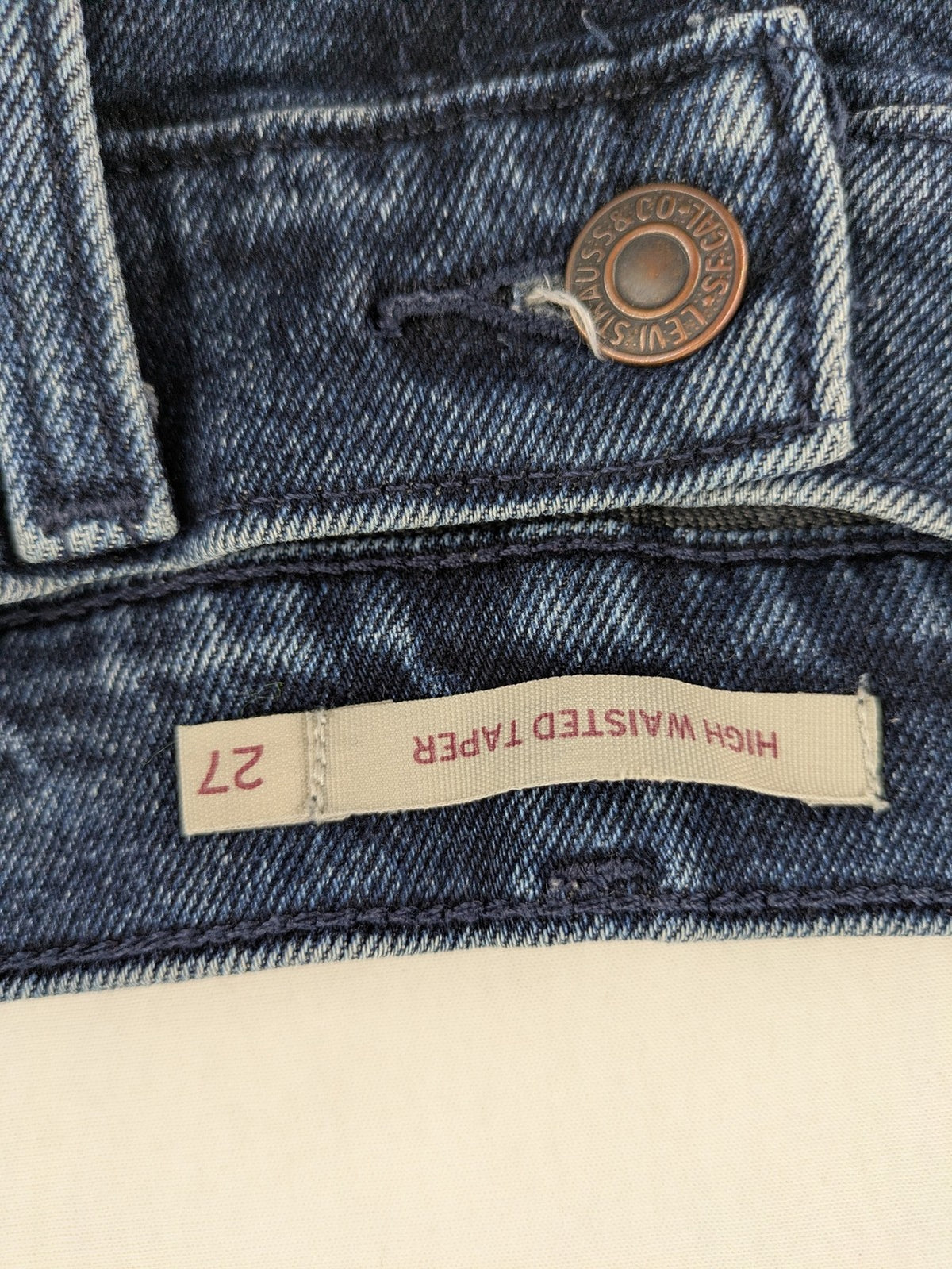 Levi's high waisted taper jeans dark blue 5-pocket design with zipper and stretch material.