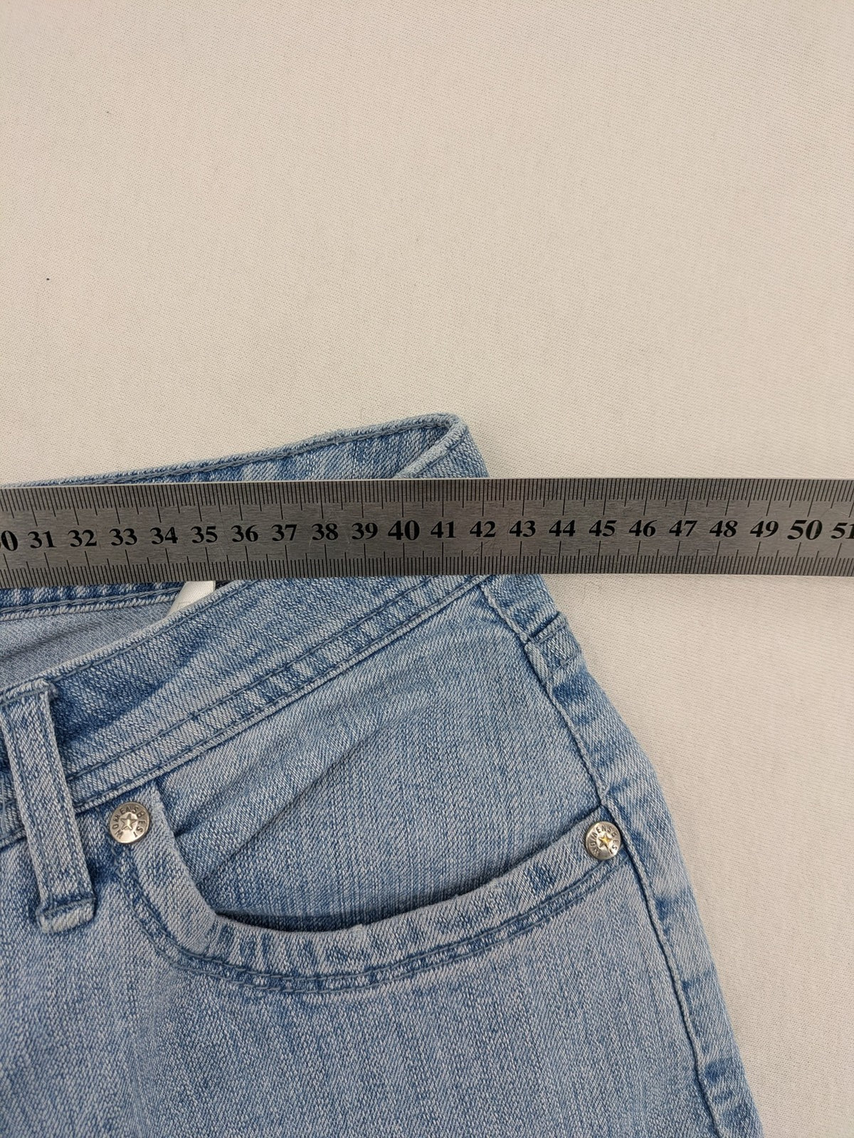 Capri blue straight jeans with 5-pocket design and embroidered details on back pockets.