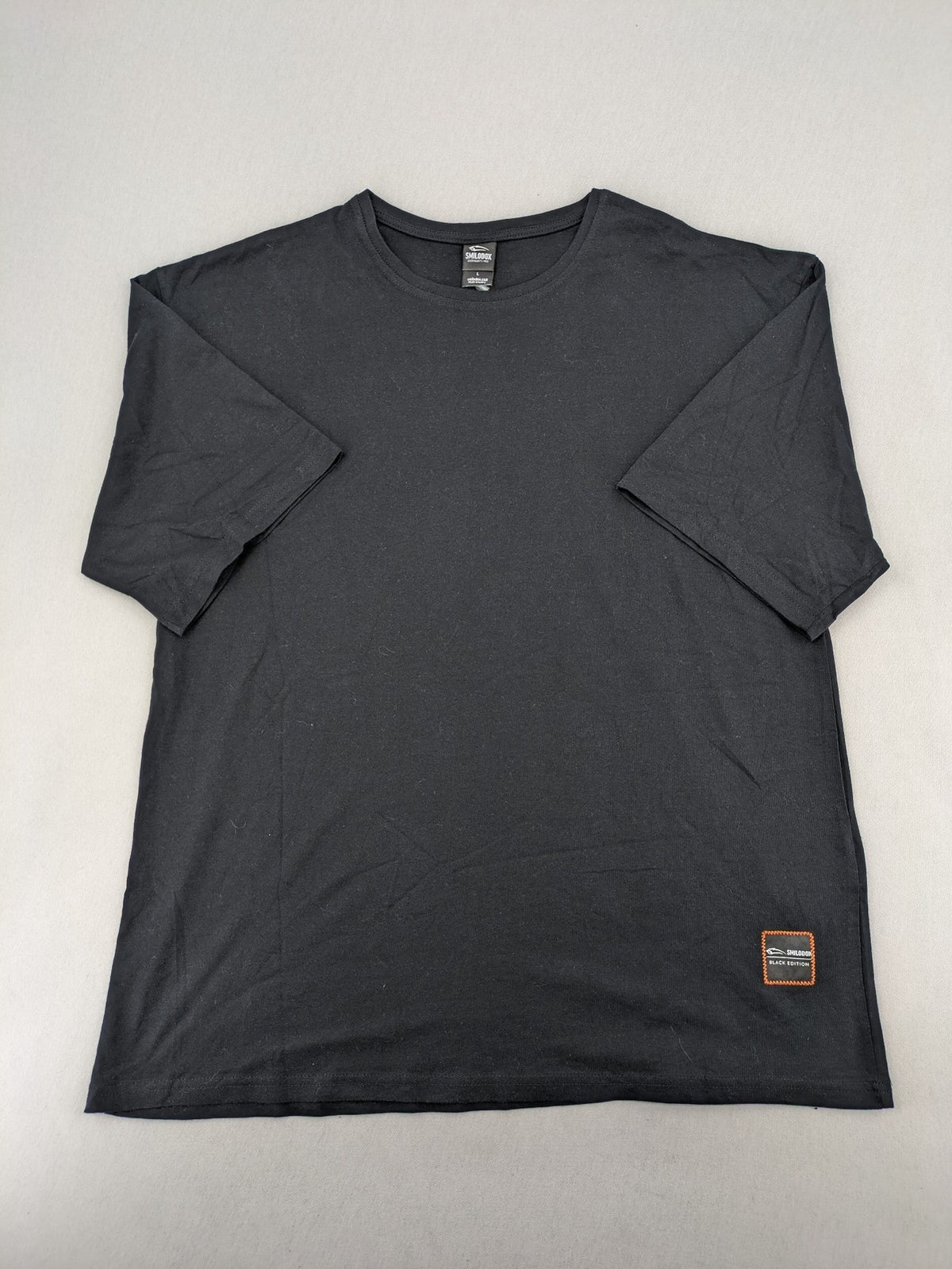 Smilodox black T-shirt minimalist design with subtle brand patch, 100% cotton.