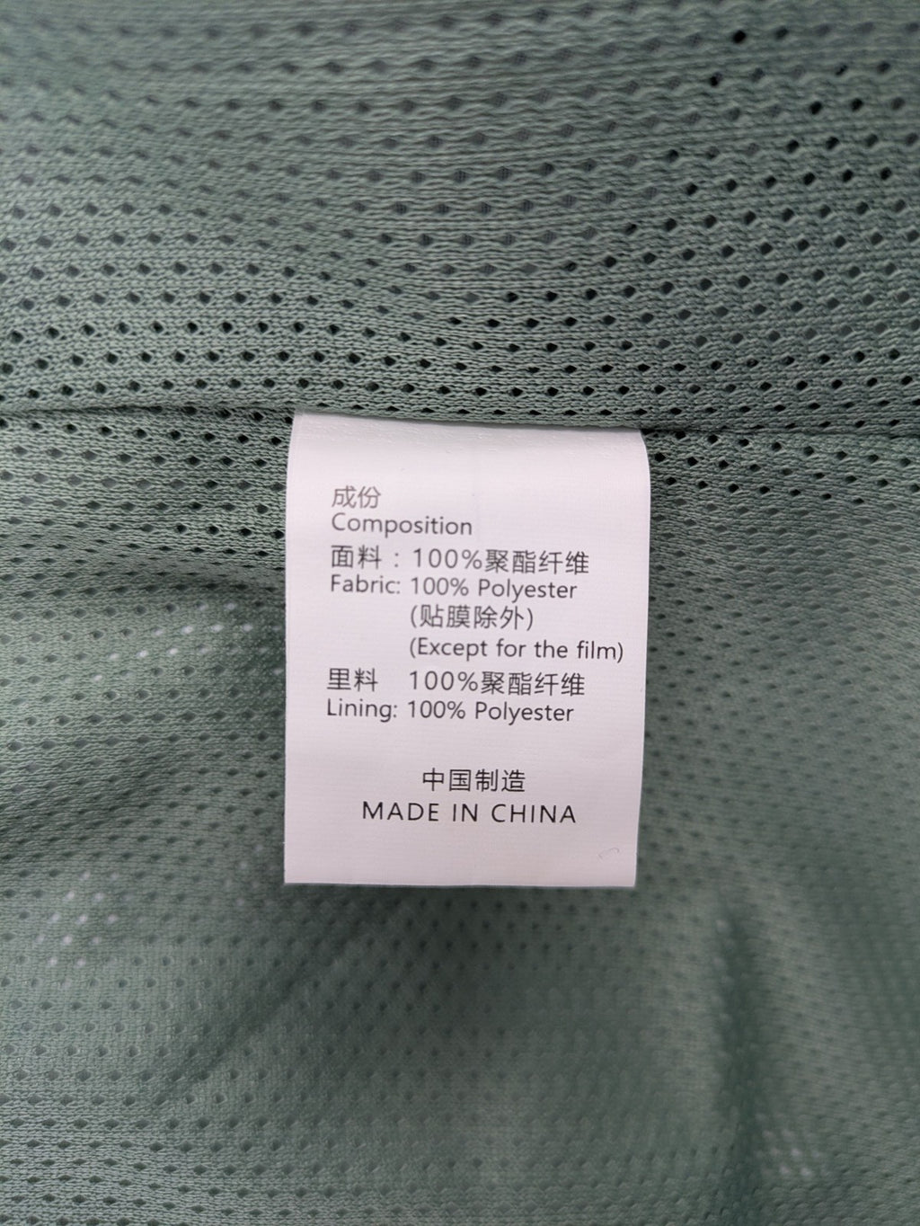 Outdoor green jacket with allover leaf print, adjustable hood, and front zipper.