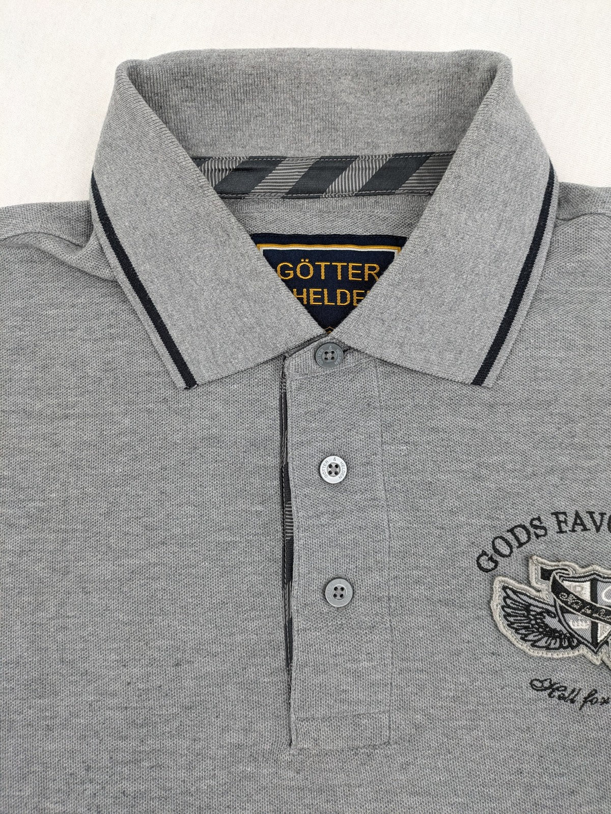 Götter & Helden grey polo shirt with "Gods Favorite" embroidery and contrasting collar details.