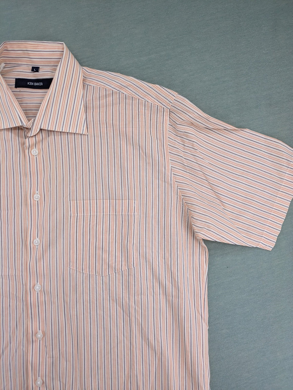 Ken Baker orange short-sleeve shirt with vertical stripes and chest pocket.