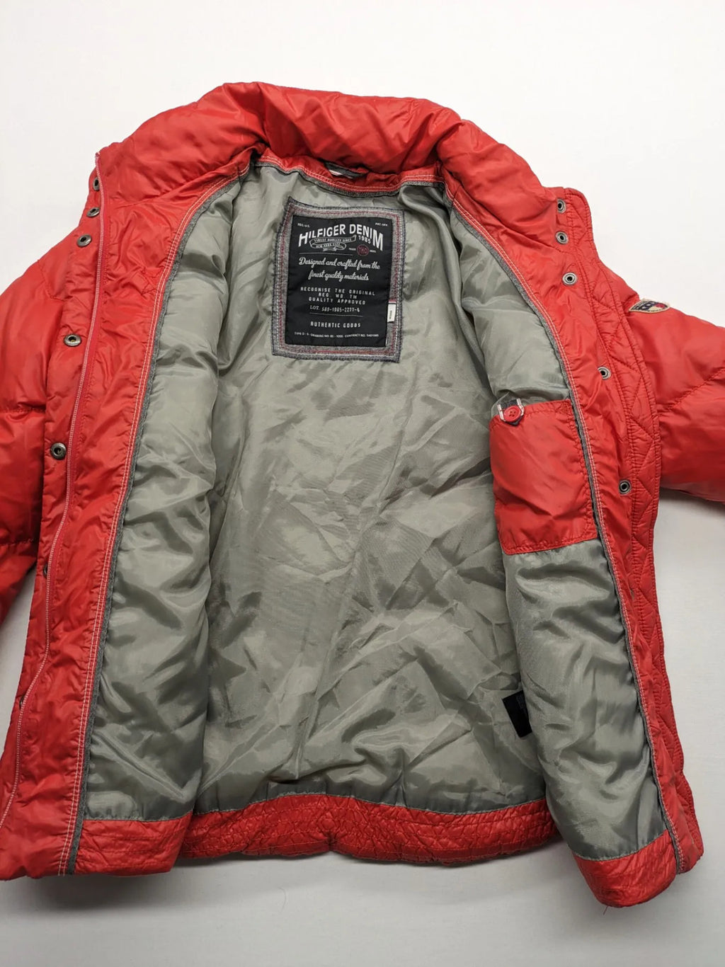 Hilfiger Denim red down jacket with quilted design, stand collar, and zip closure.
