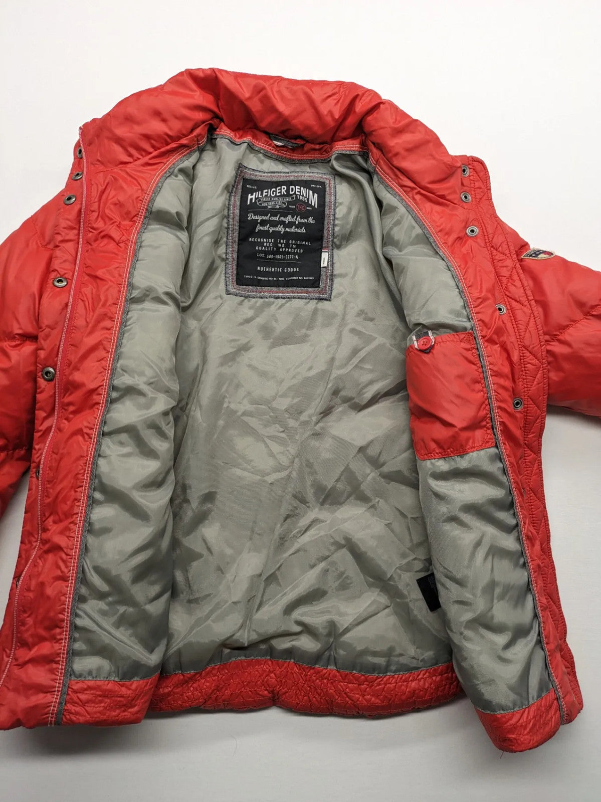 Hilfiger Denim red down jacket with quilted design, stand collar, and zip closure.