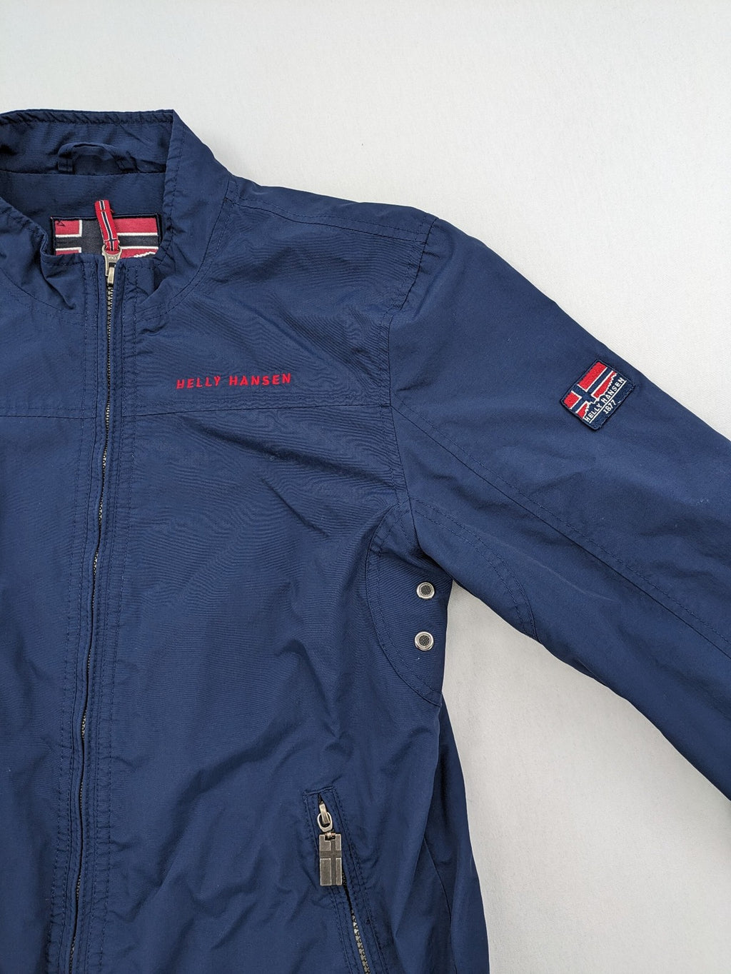 Helly Hansen navy jacket with red accents and logo, full zip, breathable mesh lining.