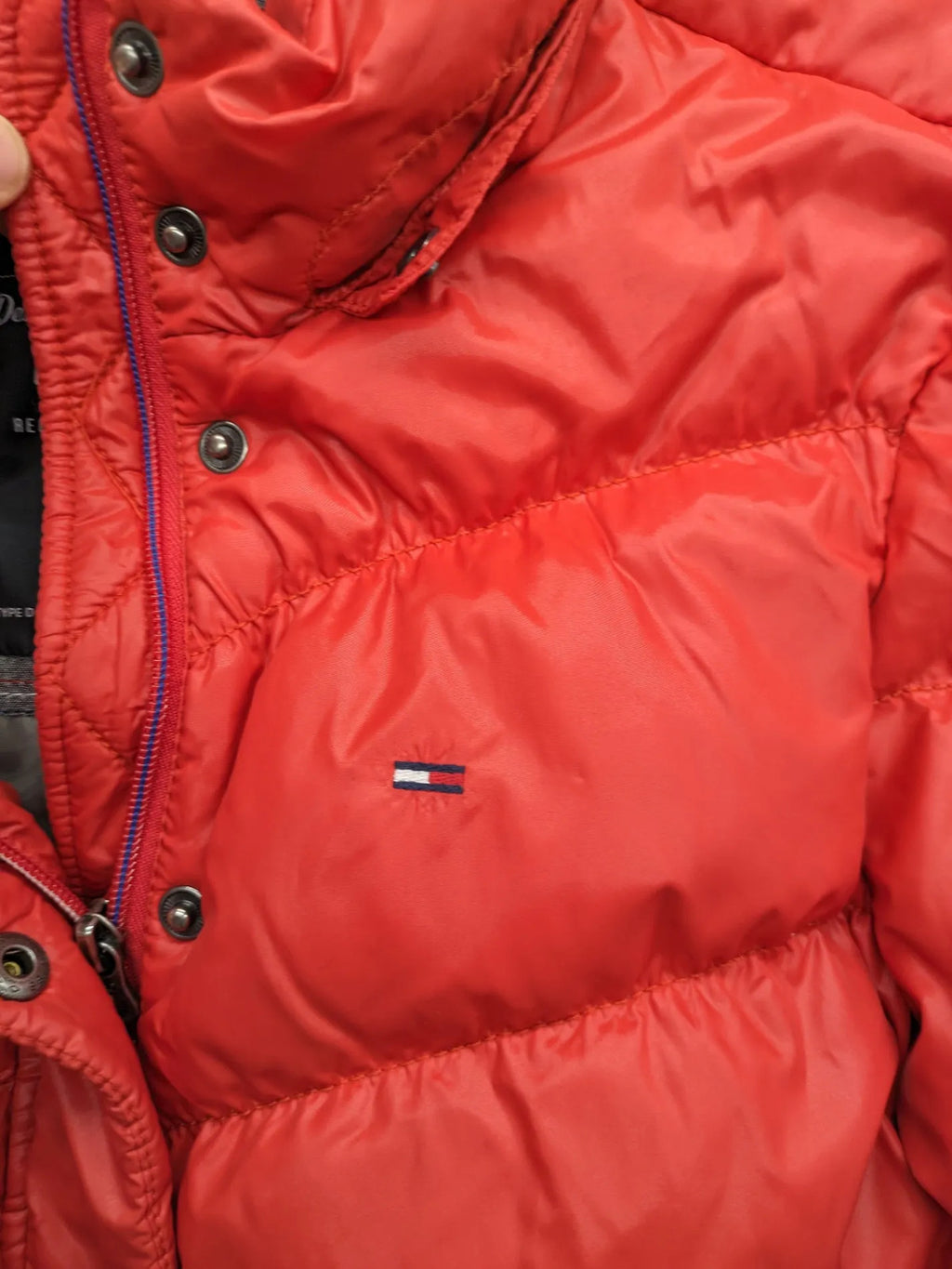 Hilfiger Denim red down jacket with quilted design, stand collar, and zip closure.