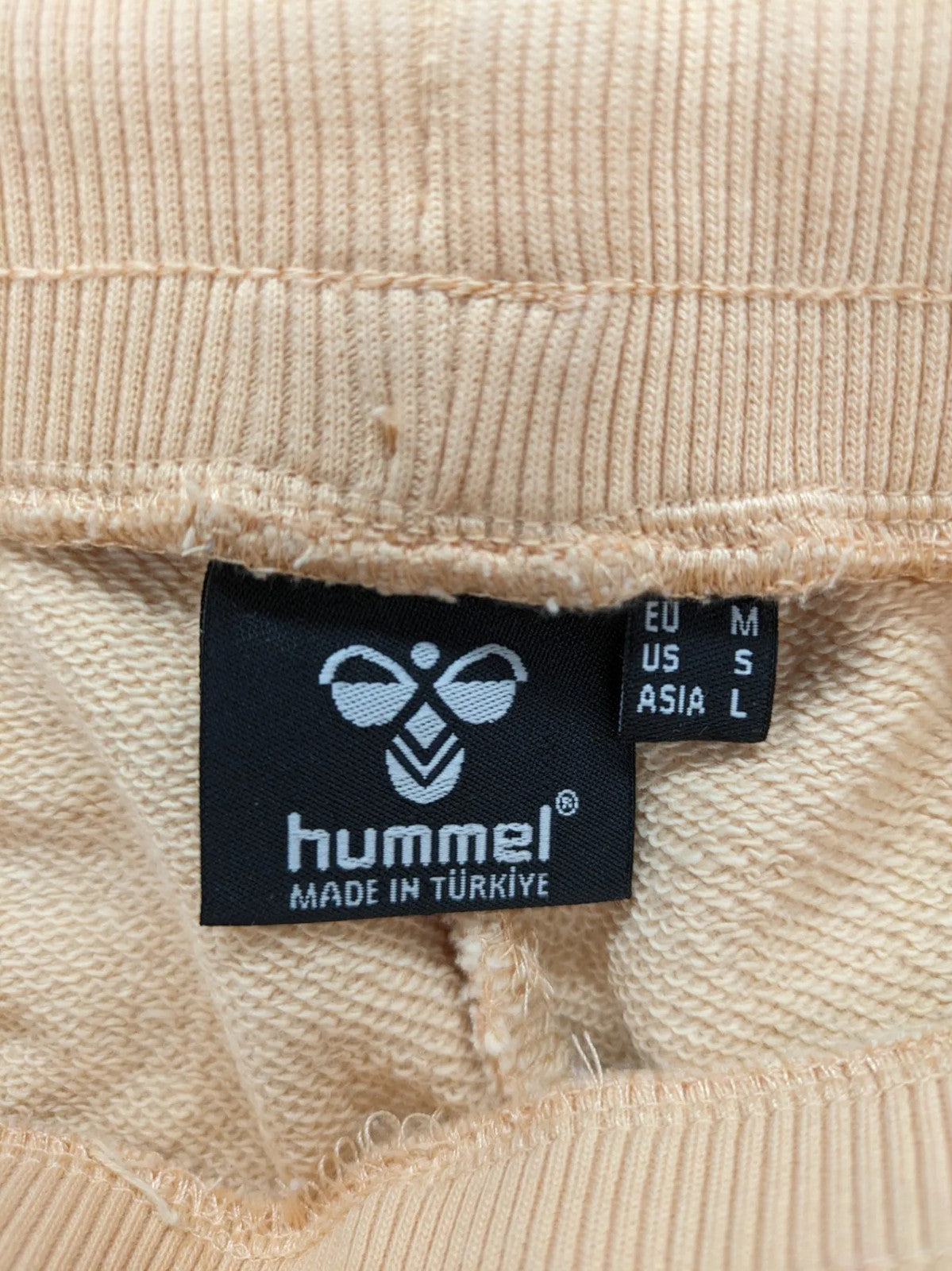 Hummel beige jogging pants with adjustable drawstring, embroidered logo, and ankle cuffs.