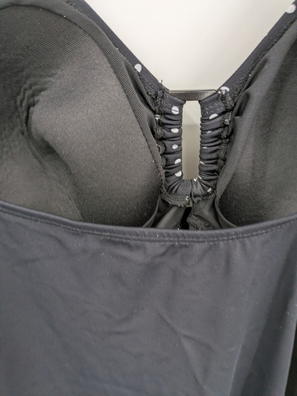Elegante black swimsuit with white polka dots, V-neck, adjustable straps, and padded cups.