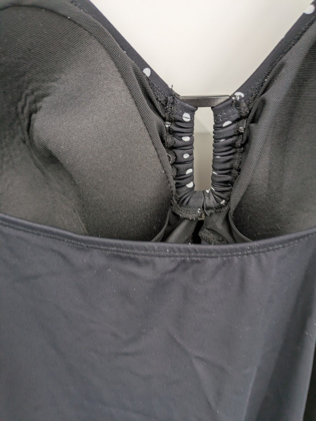 Elegante black swimsuit with white polka dots, V-neck, adjustable straps, and padded cups.