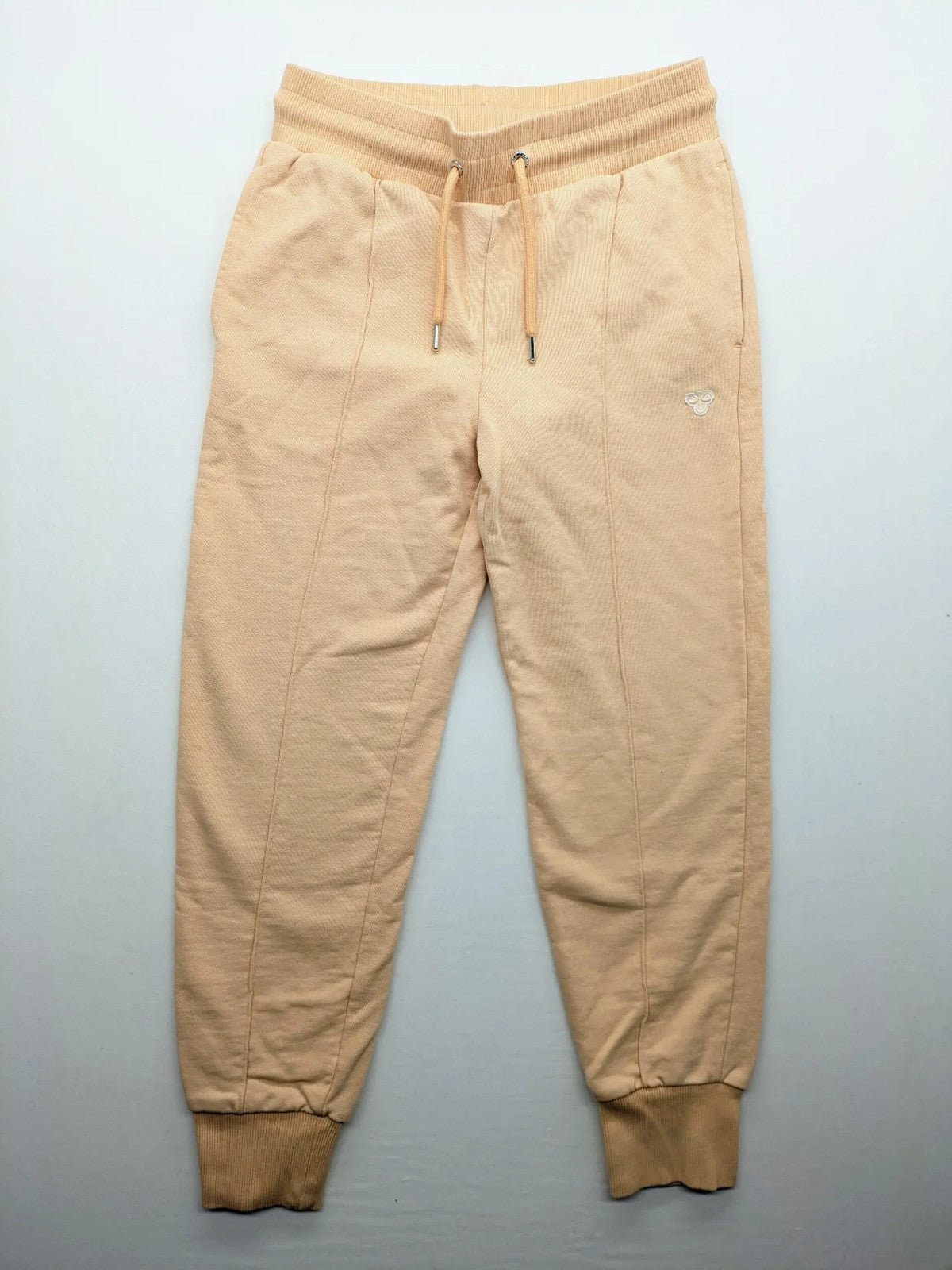 Hummel beige jogging pants with adjustable drawstring, embroidered logo, and ankle cuffs.