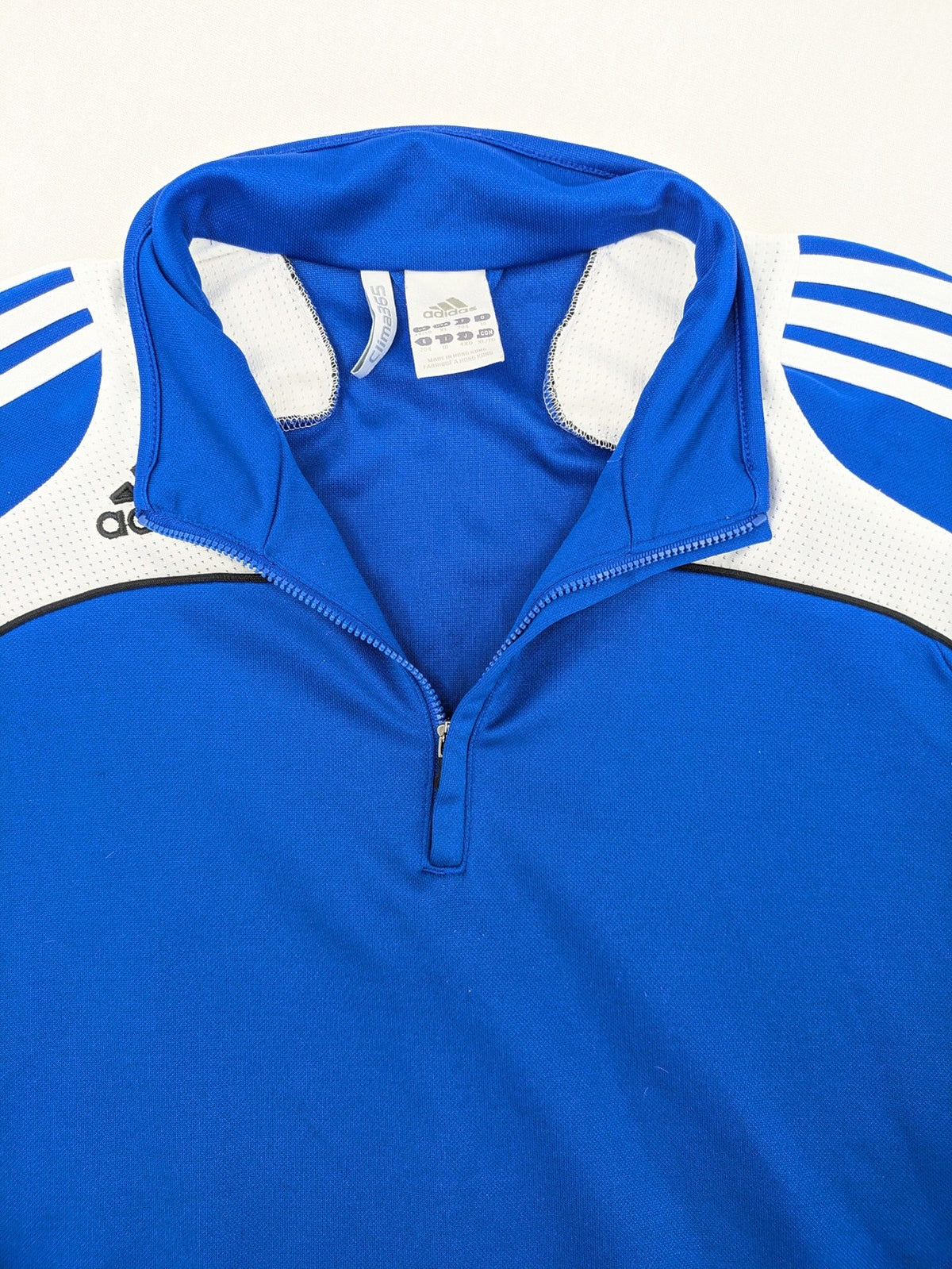 Adidas blue long sleeve top with white three stripes and 1/4 zip collar.