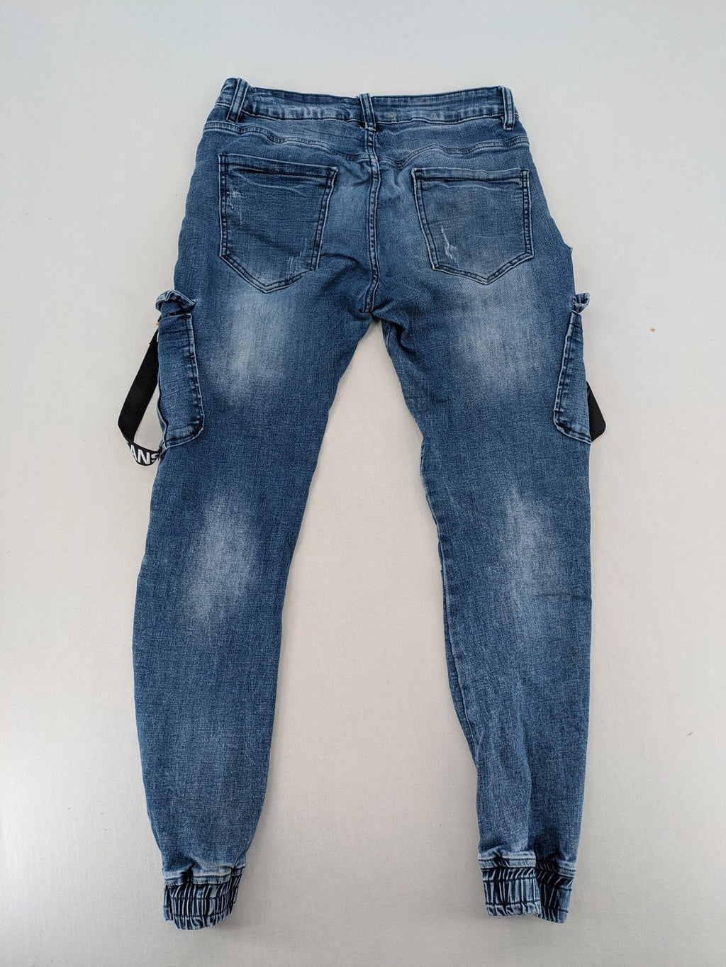 FN.G blue straight jeans with AC/DC patch, smiley face, and elastic jogger cuffs.