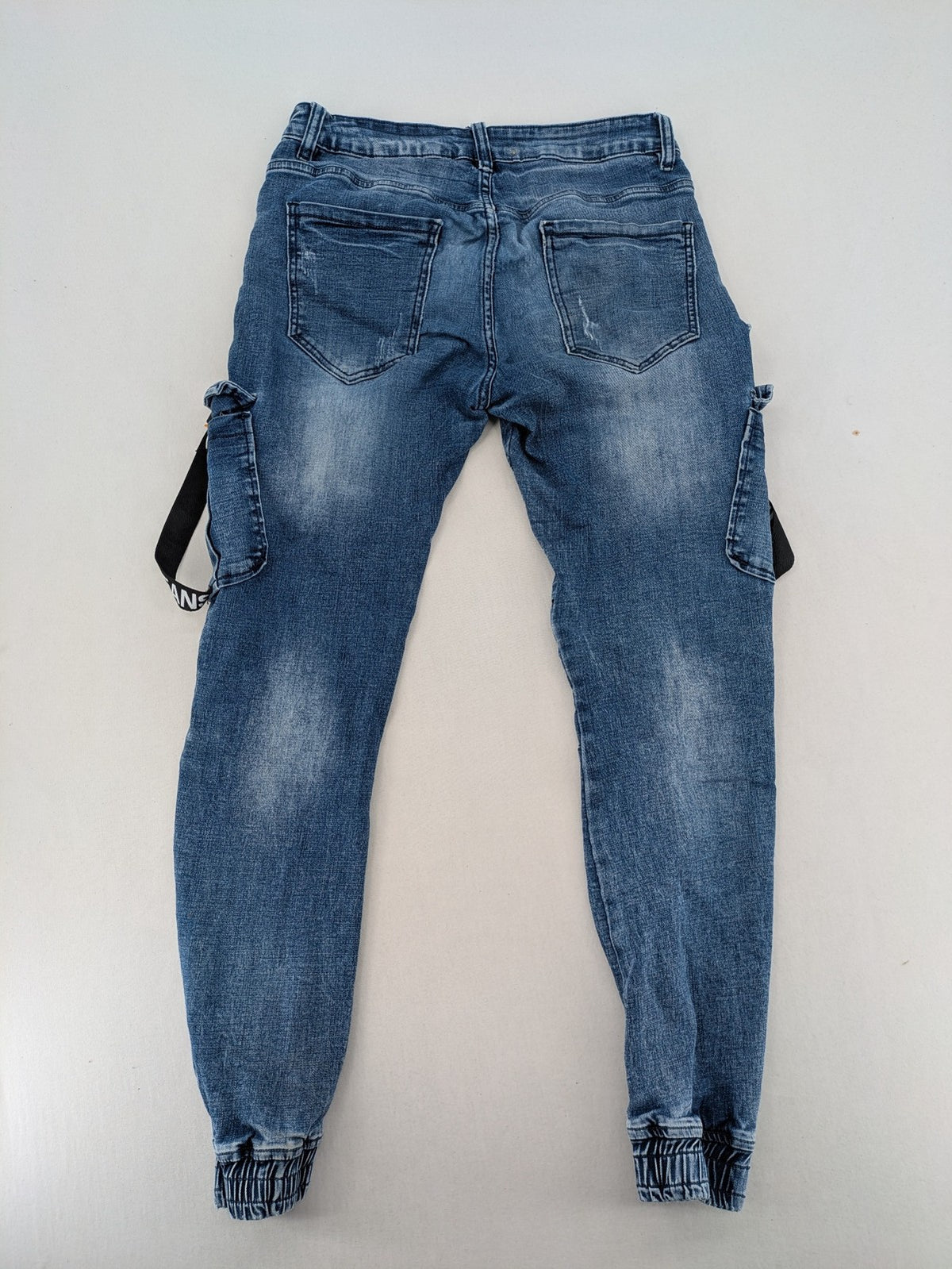 FN.G blue straight jeans with AC/DC patch, smiley face, and elastic jogger cuffs.