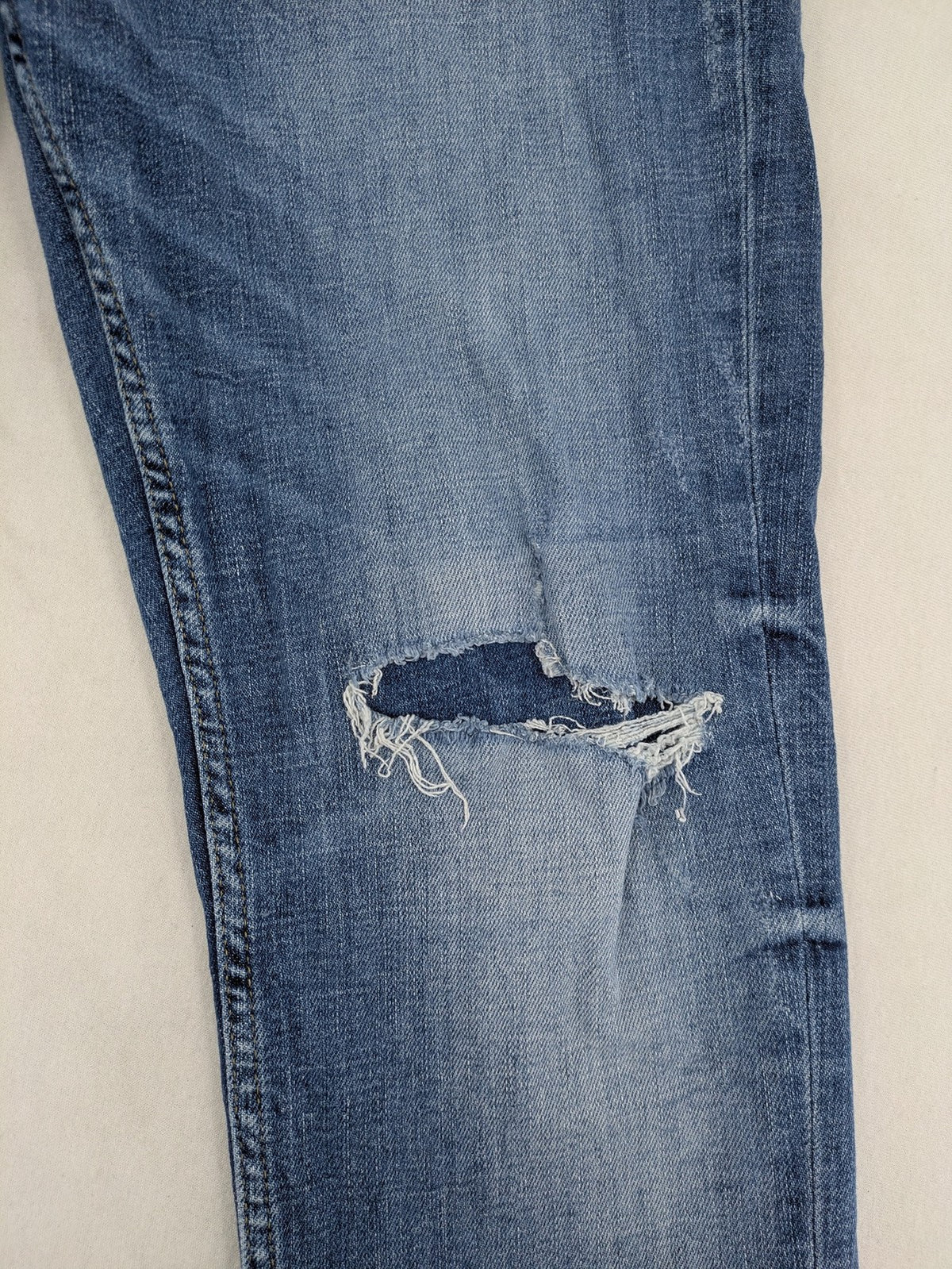 Zara blue straight jeans with distressed ripped knees and button-fly closure.