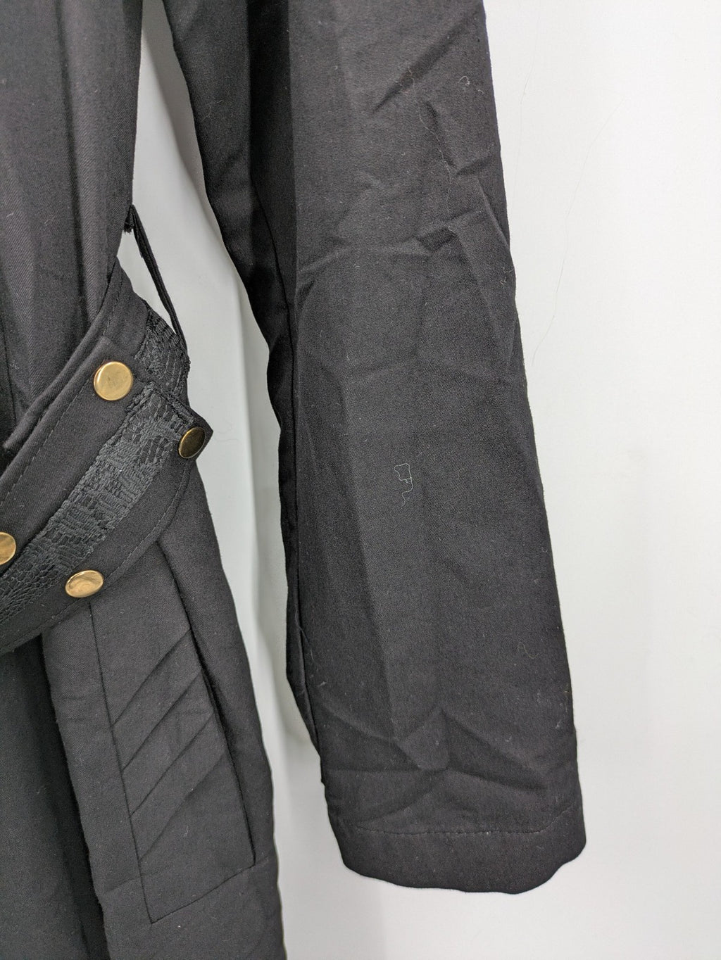 Alvina black trench coat with lace collar and gold buttons, belted waist design.