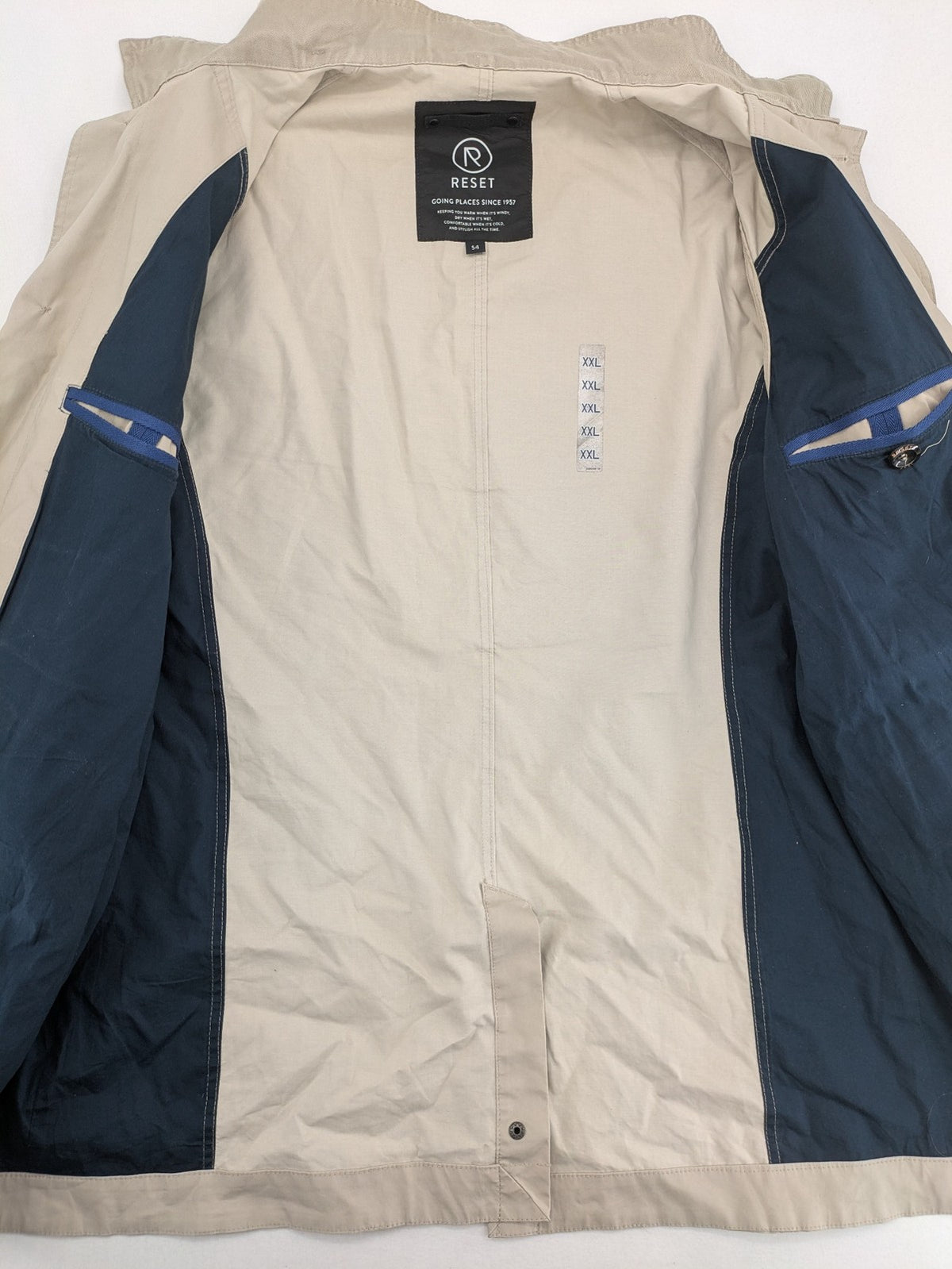 ReSET beige coat with contrasting dark blue lining and classic design details.