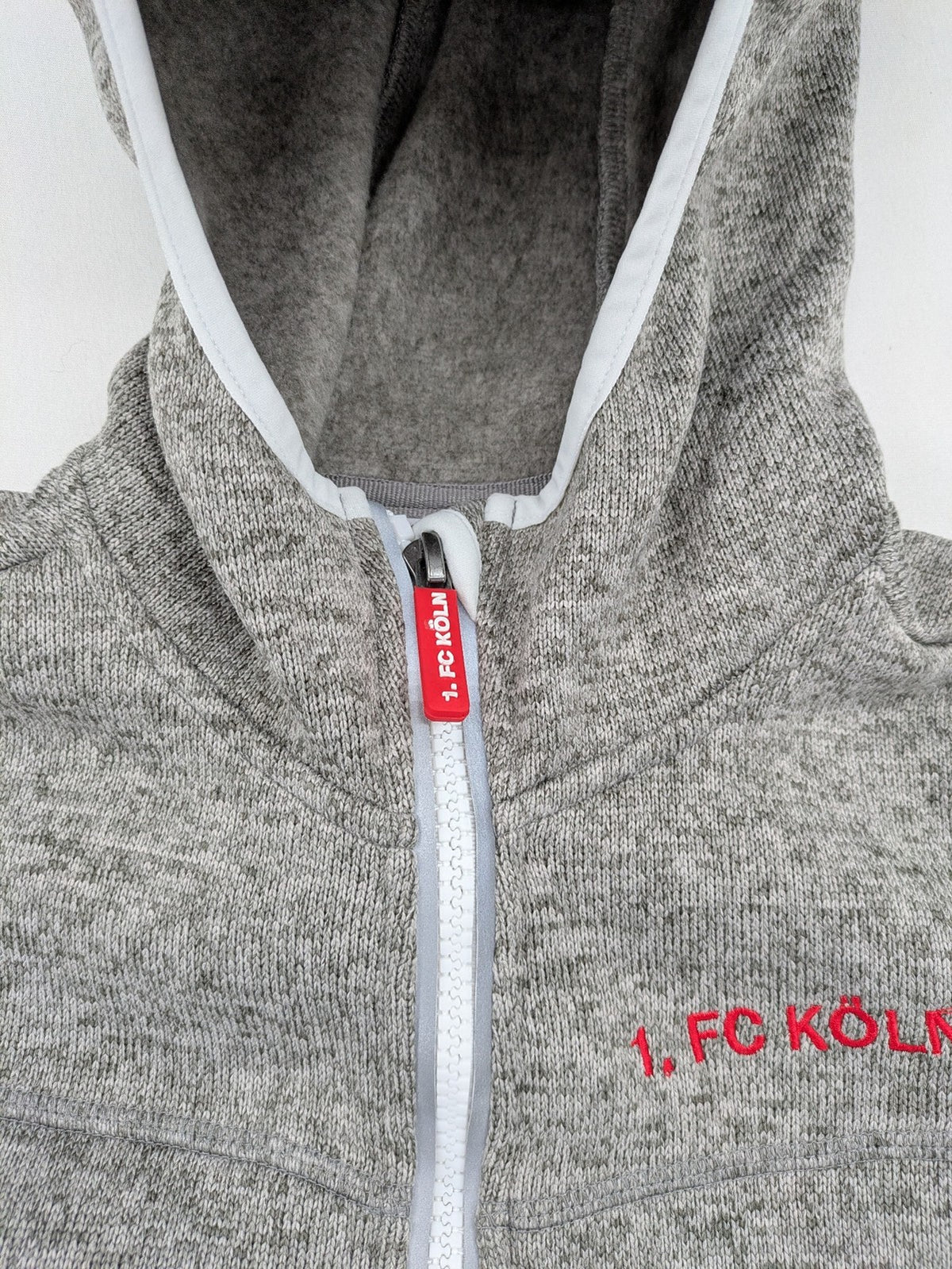 1. FC Köln grey fleece jacket with embroidered logo and hood, perfect for fans.