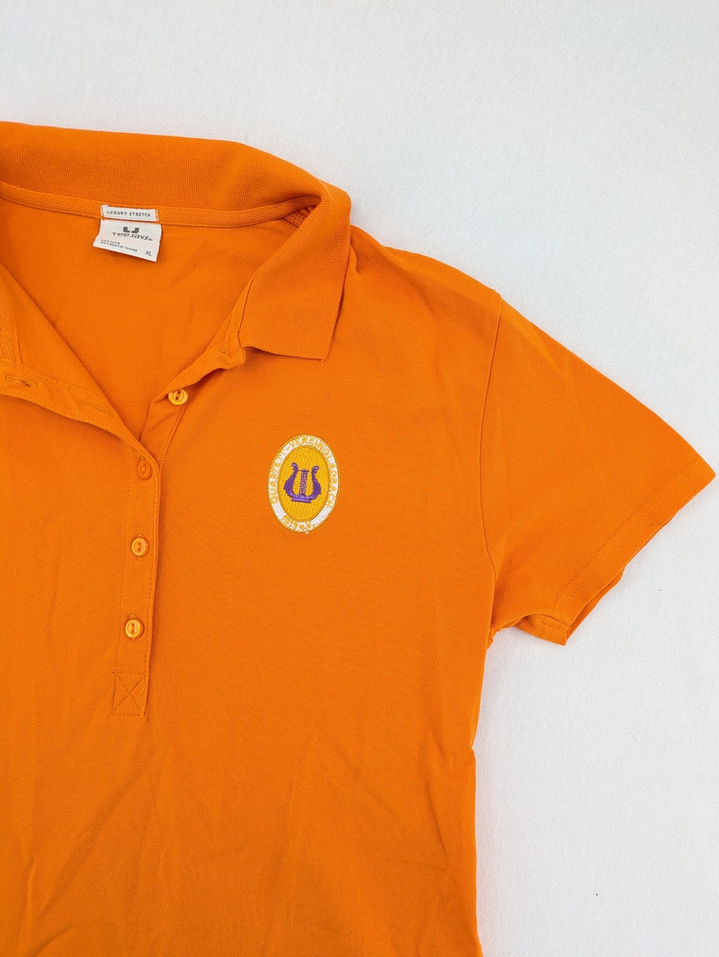Teejays orange polo shirt with embroidered logo, classic collar, and button placket.