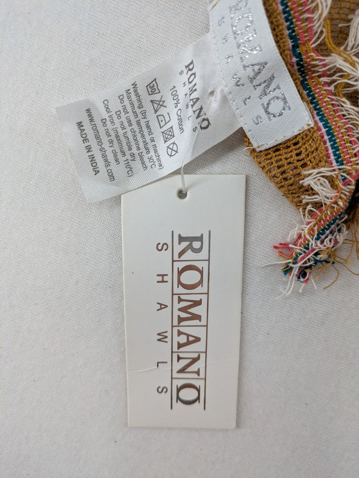 Romano multi scarf ocker with multicolored striped border and fringed edges.