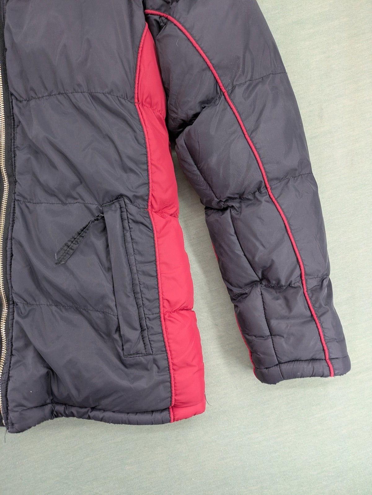Puffer grey and red jacket with fleece lining, front zipper, and side pockets.