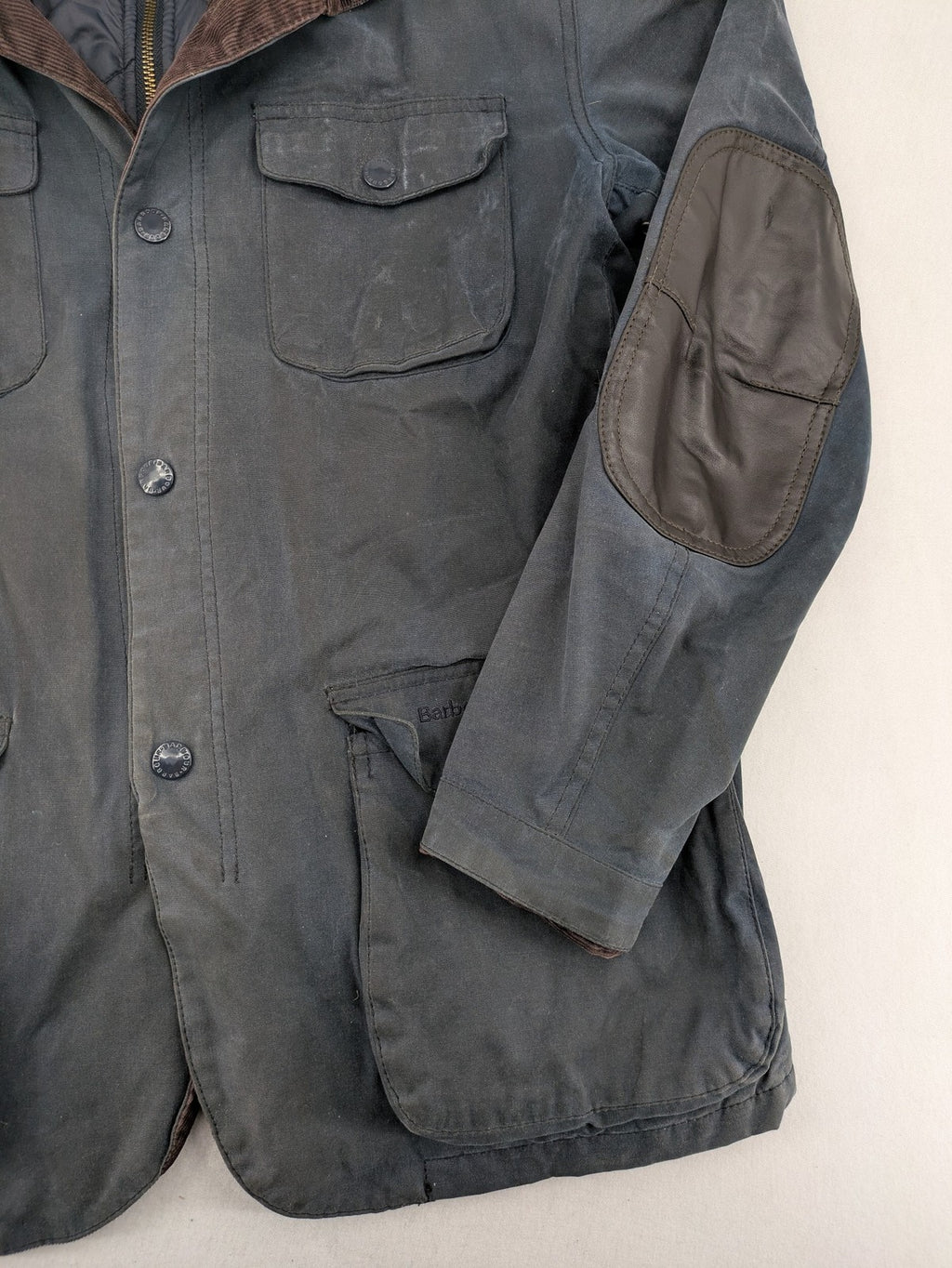 Barbour navy wax jacket with quilted lining and leather elbow patches, tartan interior.