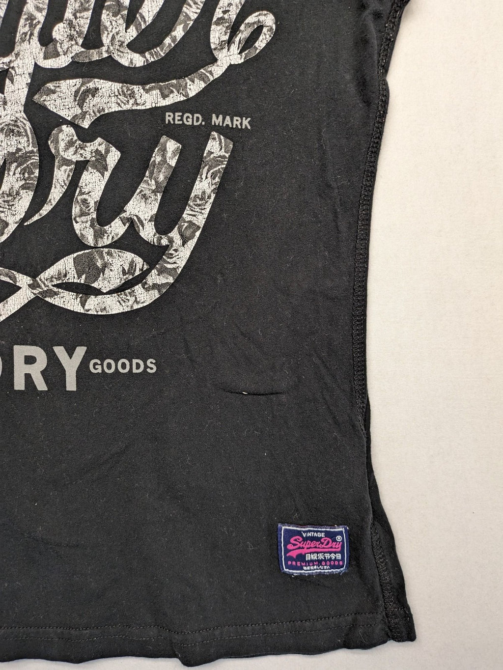 Superdry black t-shirt with large Osaka Brand logo and subtle floral pattern.